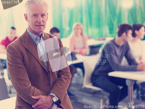 Image of portrait of in teacher in classroom with students group in backg