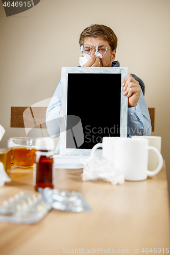 Image of Sick man while working in office, businessman caught cold, seasonal flu.