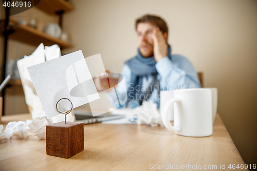 Image of Feeling sick and tired. Frustrated young man massaging his head while sitting at his working place in office