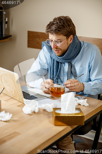 Image of Sick man while working in office, businessman caught cold, seasonal flu.