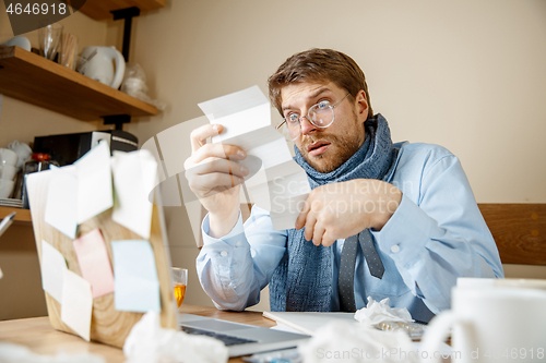 Image of Sick man while working in office, businessman caught cold, seasonal flu.