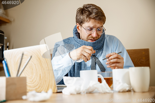 Image of Sick man while working in office, businessman caught cold, seasonal flu.