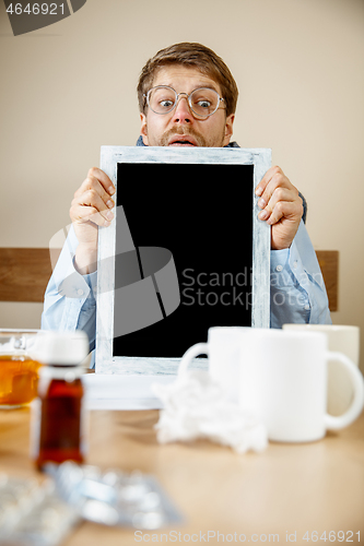 Image of Sick man while working in office, businessman caught cold, seasonal flu.