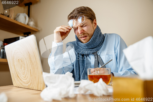 Image of Sick man while working in office, businessman caught cold, seasonal flu.