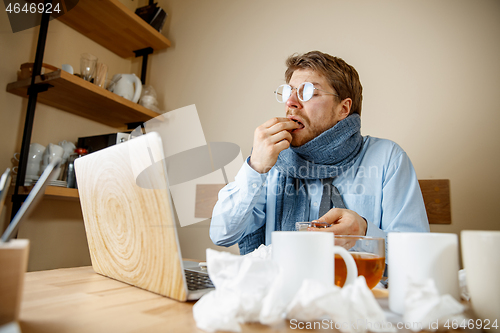 Image of Sick man while working in office, businessman caught cold, seasonal flu.