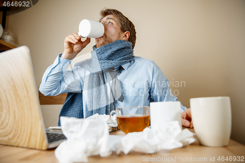 Image of Sick man while working in office, businessman caught cold, seasonal flu.