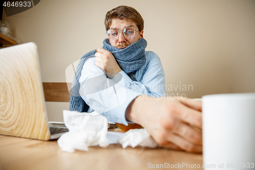 Image of Sick man while working in office, businessman caught cold, seasonal flu.