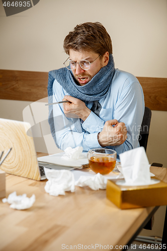 Image of Sick man while working in office, businessman caught cold, seasonal flu.