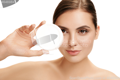 Image of Cute girl preparing to start her day. She is applying moisturizer cream on face.