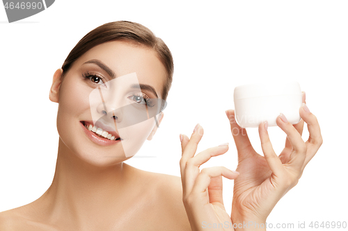 Image of Cute girl preparing to start her day. She is applying moisturizer cream on face.