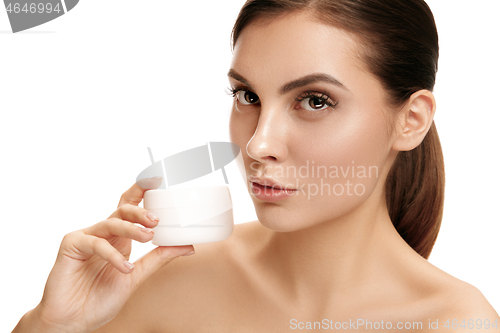 Image of Cute girl preparing to start her day. She is applying moisturizer cream on face.