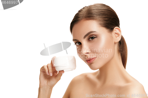 Image of Cute girl preparing to start her day. She is applying moisturizer cream on face.