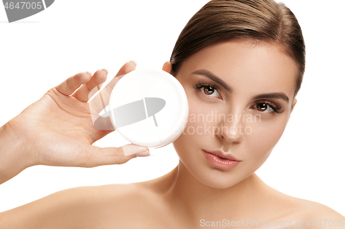 Image of Cute girl preparing to start her day. She is applying moisturizer cream on face.