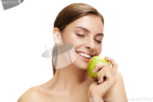 Image of portrait of attractive caucasian smiling woman isolated on white studio shot eating green apple