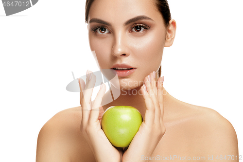 Image of portrait of attractive caucasian smiling woman isolated on white studio shot eating green apple