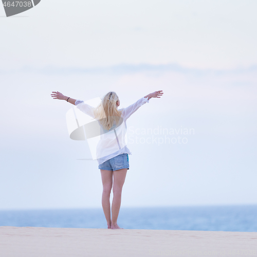 Image of Free woman enjoying freedom on beach in morning.