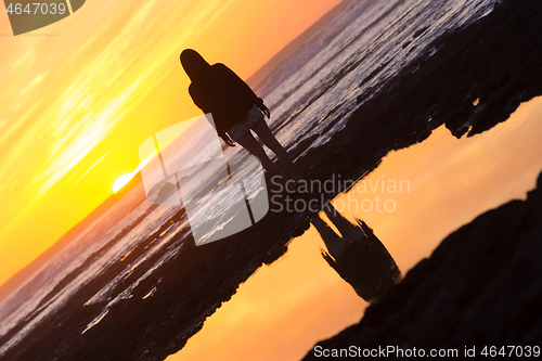 Image of Silhouette of meditative, sensual blonde woman watching sunset at the beach.