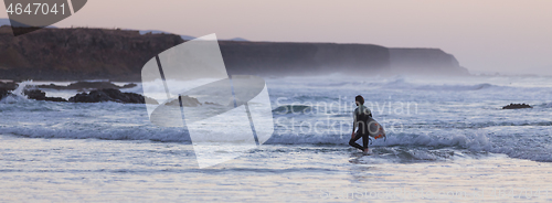 Image of Surfers on beach with surfboard.