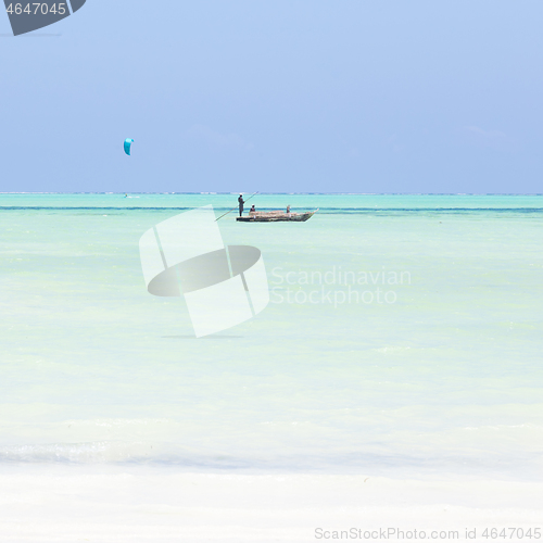 Image of fishing boat and a kite surfer on picture perfect white sandy beach with turquoise blue sea, Paje, Zanzibar, Tanzania.