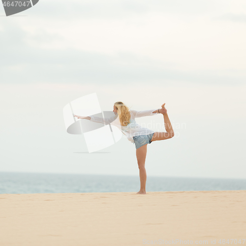 Image of Relaxed woman enjoying enjoying peace and freedom during her morning walk on vacations, streching in yoga like pose at beach