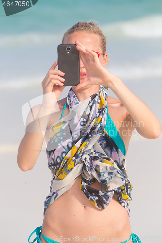 Image of Beautiful caucasian woman taking a photo on tropical beach summer vacations using her cell phone.