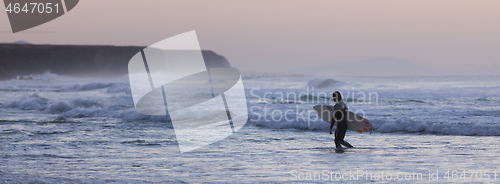 Image of Surfers on beach with surfboard.