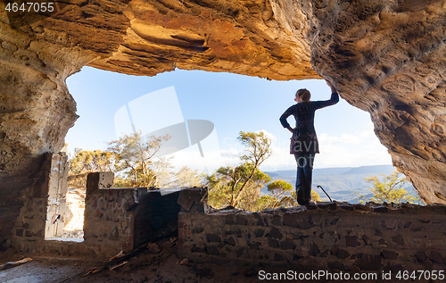 Image of Woman looking out to mountain views from a cave