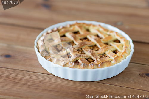 Image of apple pie in baking mold on wooden table