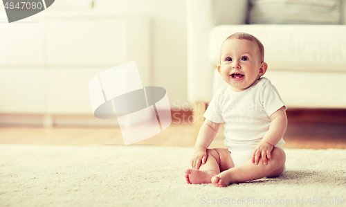 Image of happy baby boy or girl sitting on floor at home