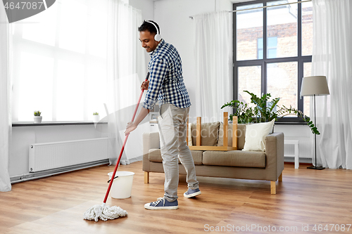 Image of man in headphones with mop cleaning floor at home