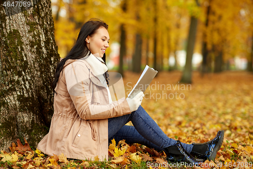 Image of woman reading book at autumn park