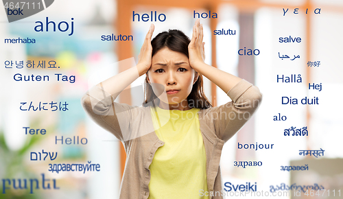 Image of stressed asian woman over foreign words