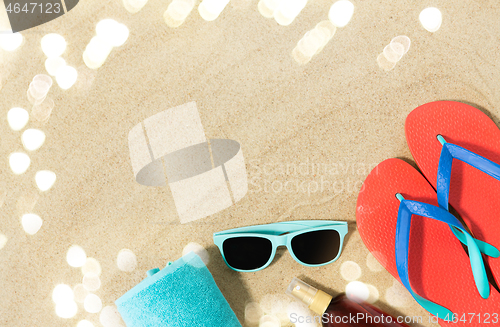 Image of straw hat, flip flops and sunglasses on beach sand