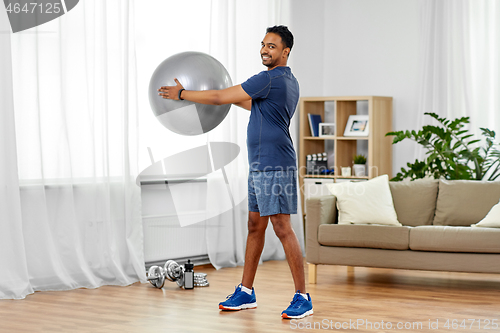 Image of indian man exercising with fitness ball at home