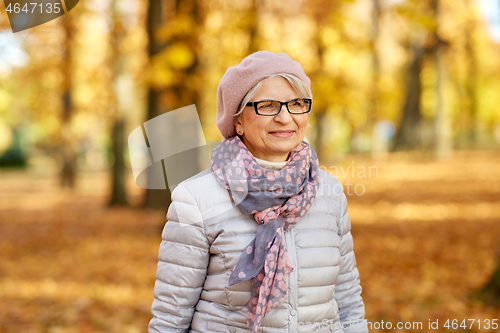 Image of portrait of happy senior woman at autumn park