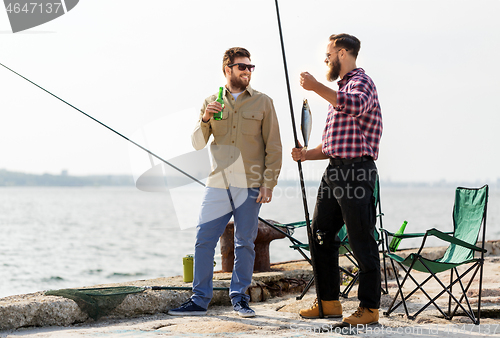 Image of male friends with fishing rods and beer on pier