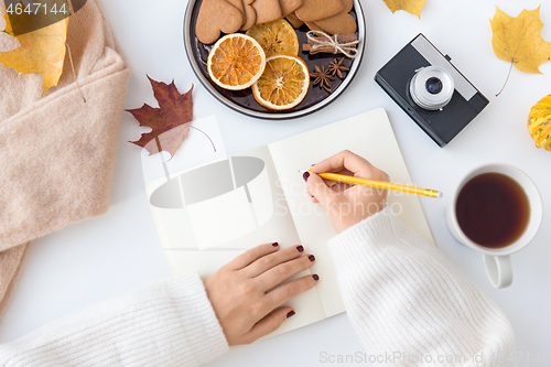 Image of woman\'s hands writing to notebook in autumn