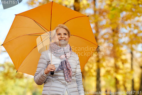 Image of happy senior woman with umbrella at autumn park