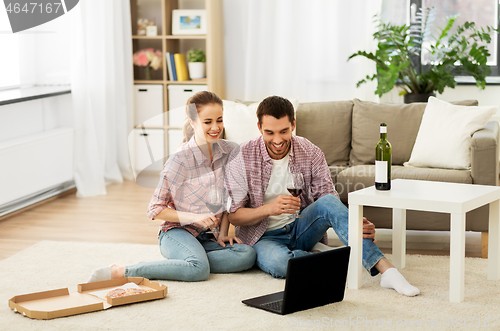 Image of happy couple with laptop drinking red wine at home