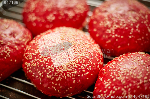 Image of Fresh baked red homemade burger buns with sesame top view. Placed on metal grill.