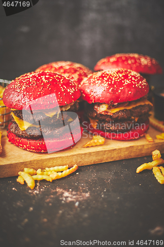 Image of A set of red bun homemade delicious burgers of beef, bacon, cheese, grilled onion on a dark rusty