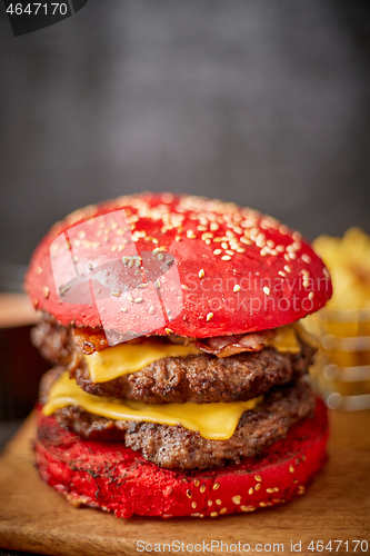 Image of Homemade red sesame bun double bacon cheese burger. Served with french fries on wooden board.