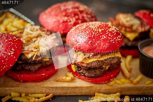 Image of A set of red bun homemade delicious burgers of beef, bacon, cheese, grilled onion on a dark rusty