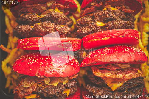 Image of A set of red bun homemade delicious burgers of beef, bacon, cheese, grilled onion on a dark rusty