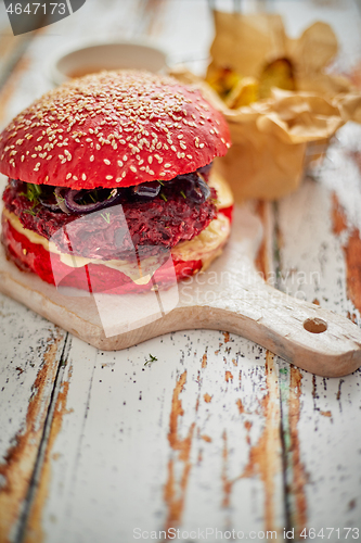 Image of Homemade vegetable beetroot burgers. Red colored sesame bun. Served with goat cheese, feta