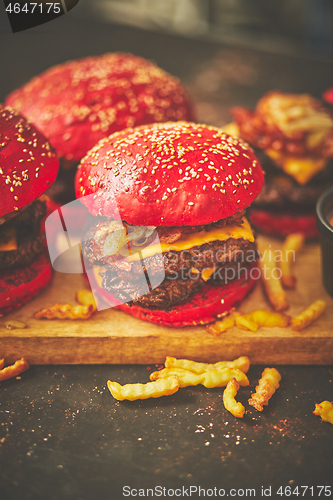 Image of A set of red bun homemade delicious burgers of beef, bacon, cheese, grilled onion on a dark rusty