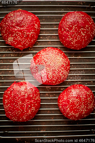 Image of Fresh baked red homemade burger buns with sesame top view. Placed on metal grill.