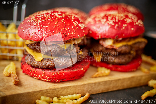 Image of Set of four homemade giant double becon cheese burgers. Served with french fries on wooden board.