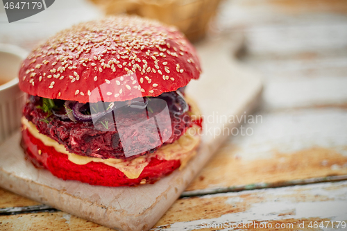 Image of Homemade vegetable beetroot burgers. Red colored sesame bun. Served with goat cheese, feta