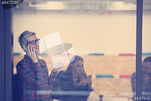 Image of business woman at office speaking by phone  team on meeting in b